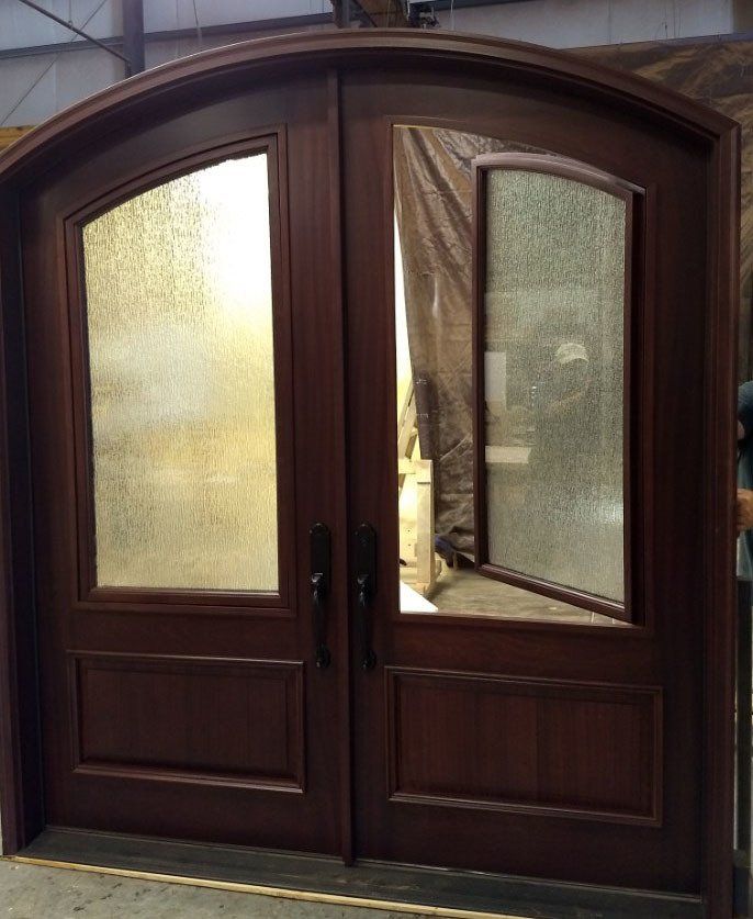 A pair of arched wooden doors with clear glass