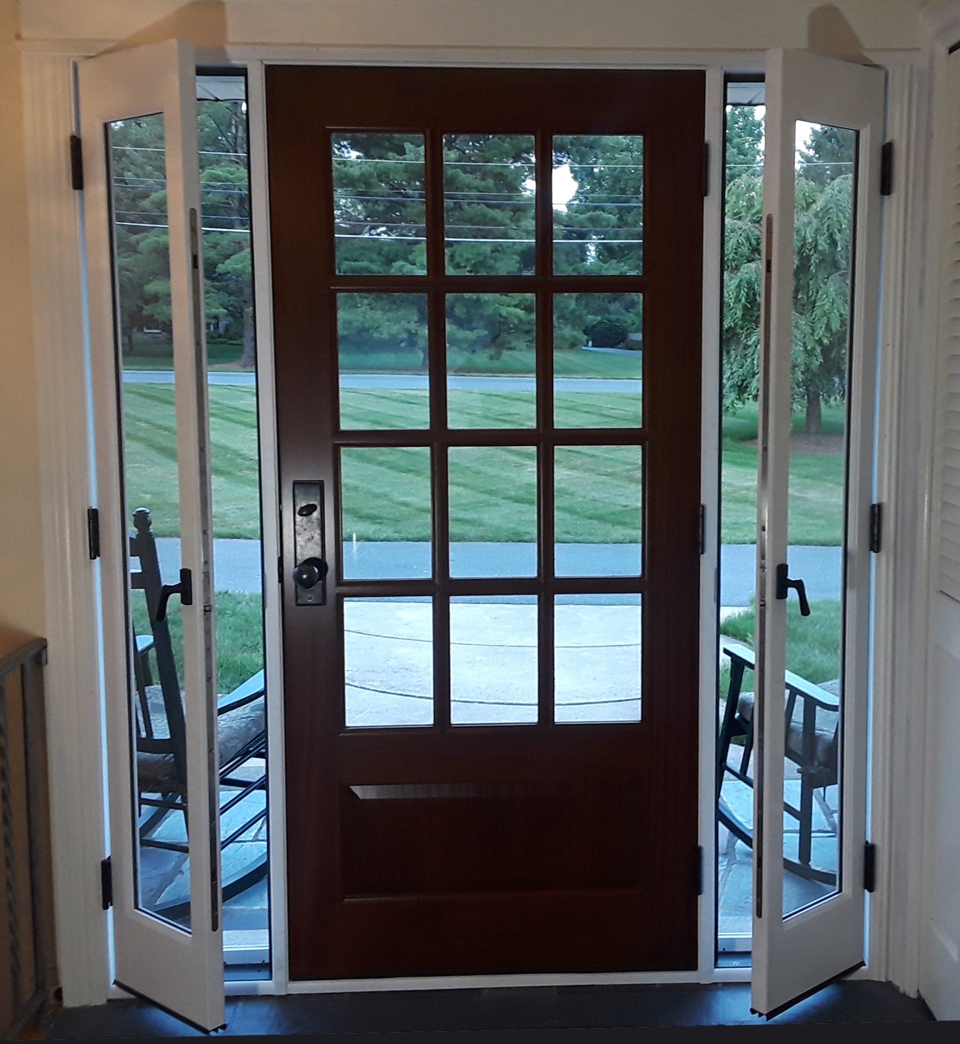 A wooden door with glass panels is open to a yard