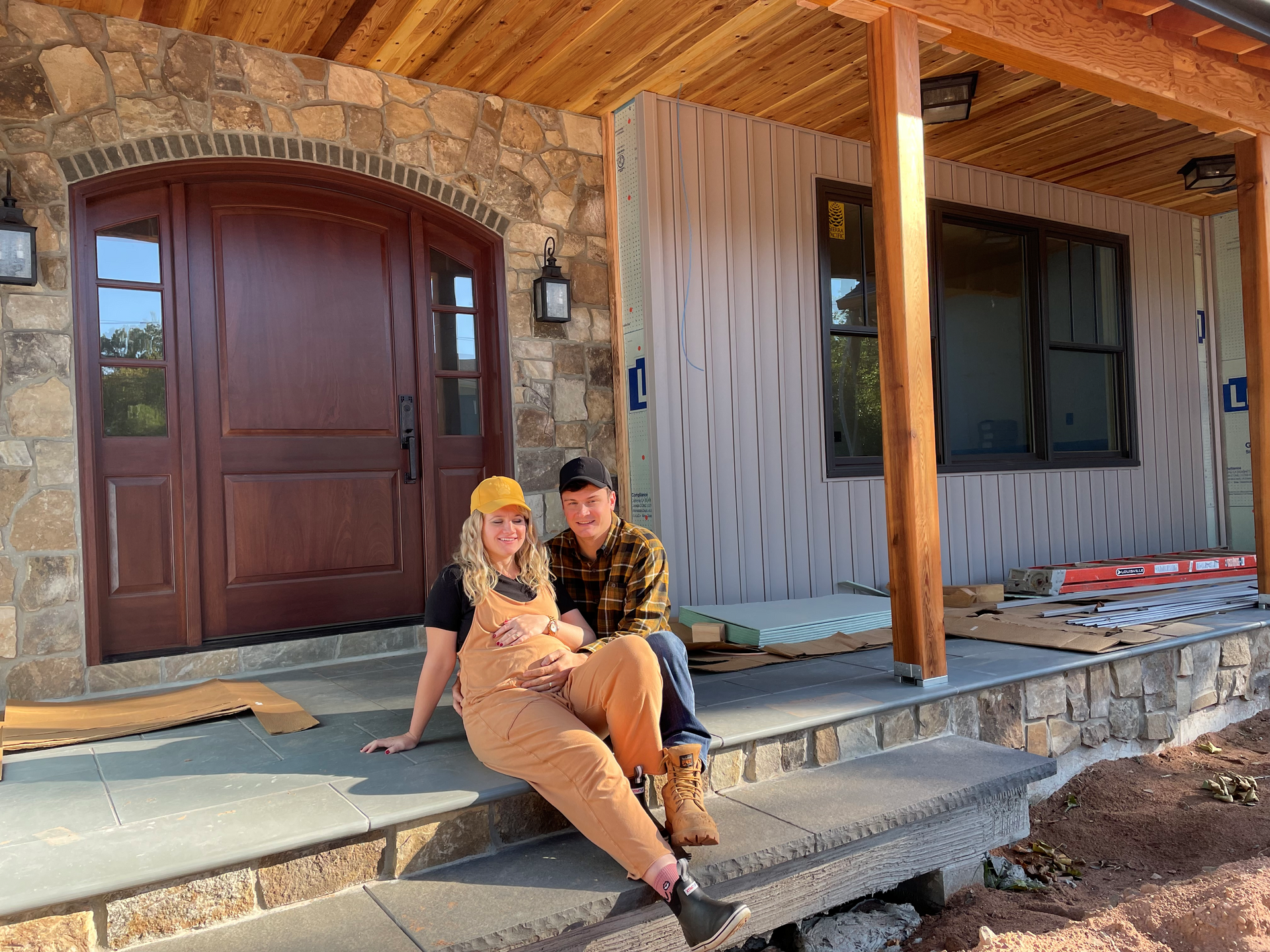 A man and a woman are sitting on the porch of a house under construction.