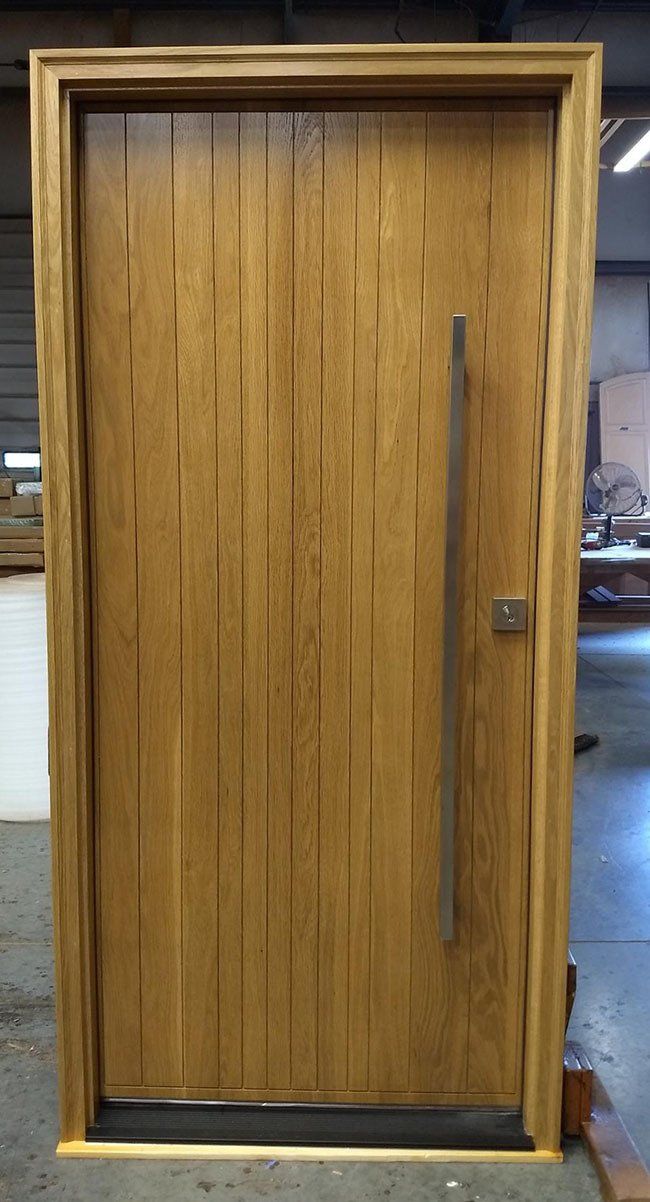 A wooden door with a metal handle is sitting on a concrete floor.