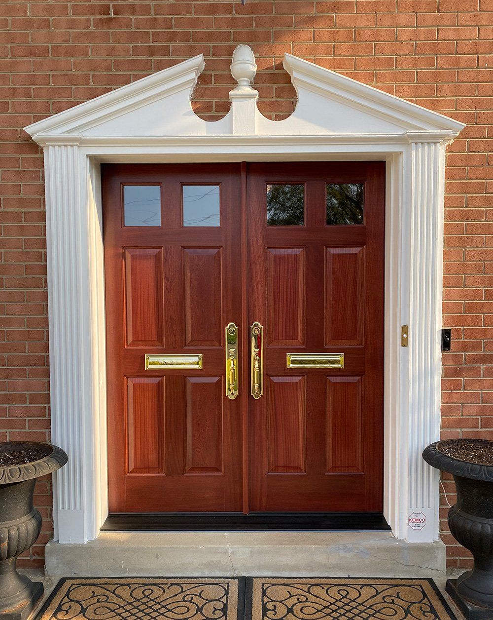A red double door with a white trim on a brick building