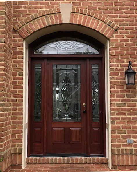 A brick building with a wooden door and a lamp on the side.