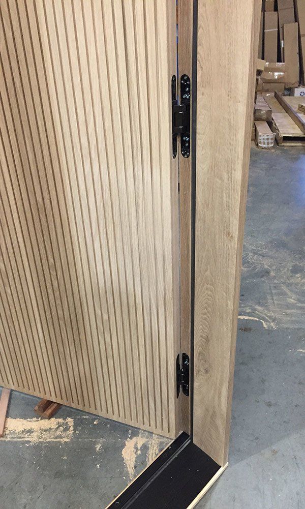 A close up of a wooden door with black hinges in a warehouse.