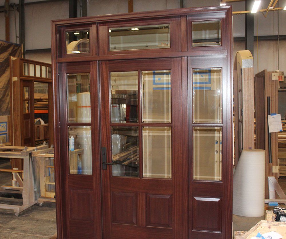 Solid wood front entry door made from Sapele mahogany has 4 glass panes in upper panel.  Pre-hung with side lites and door transom
