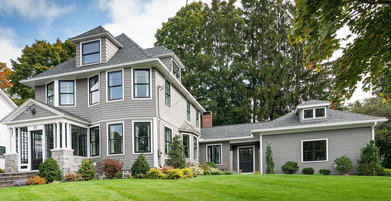 A large house with a lot of windows is sitting on top of a lush green lawn.