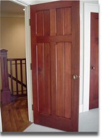A wooden door is open to a staircase with a railing