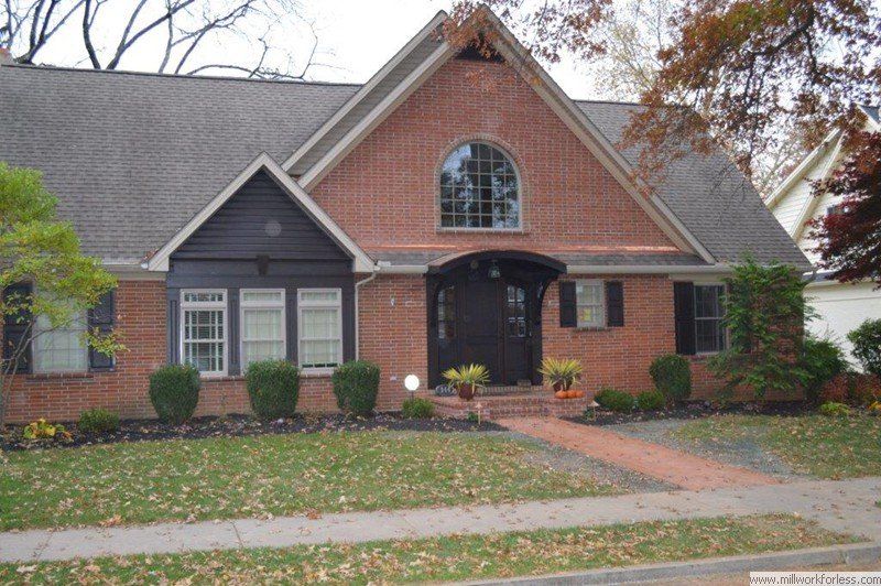 A brick house with a black door and shutters