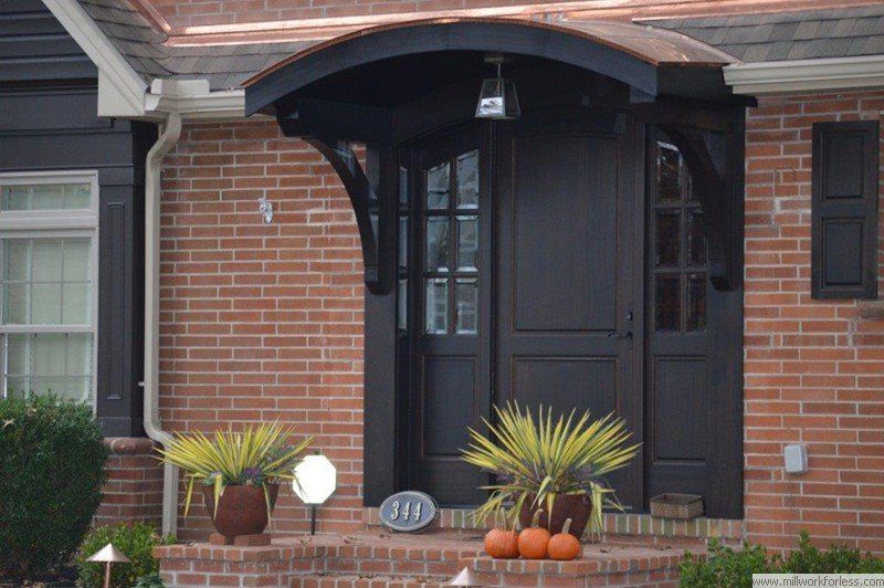 A brick house with a black door and a copper roof
