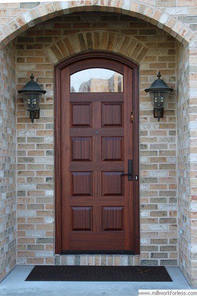 A wooden door with a brick wall behind it