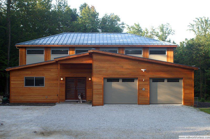A large wooden house with three garage doors and a metal roof