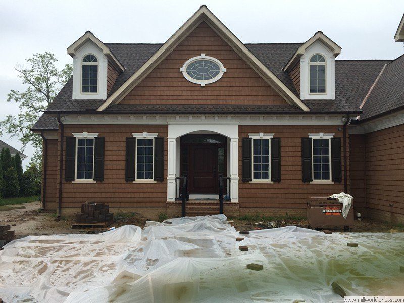 A large brown house with white trim and black shutters