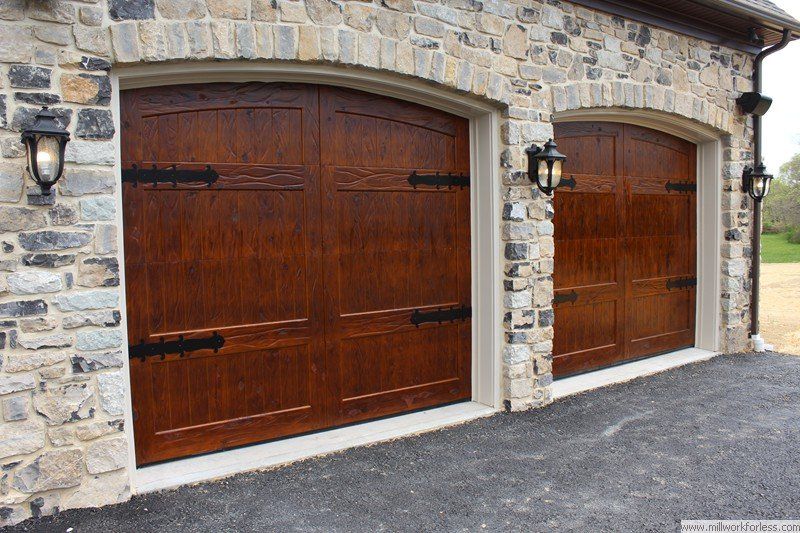 A pair of wooden garage doors on a stone building.