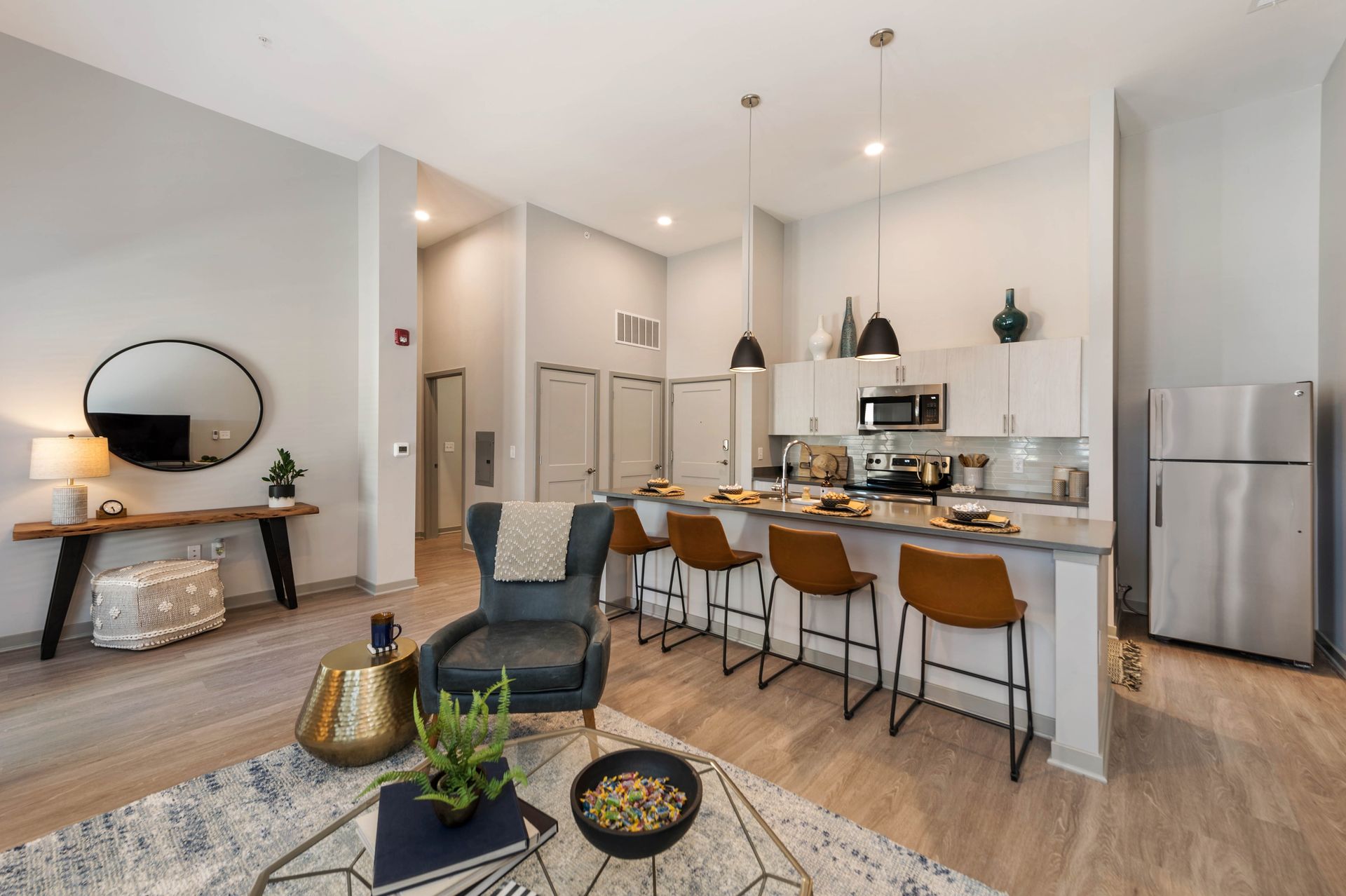 Modern kitchen and living area featuring a bar counter with seating, stylish decor, and natural lighting.