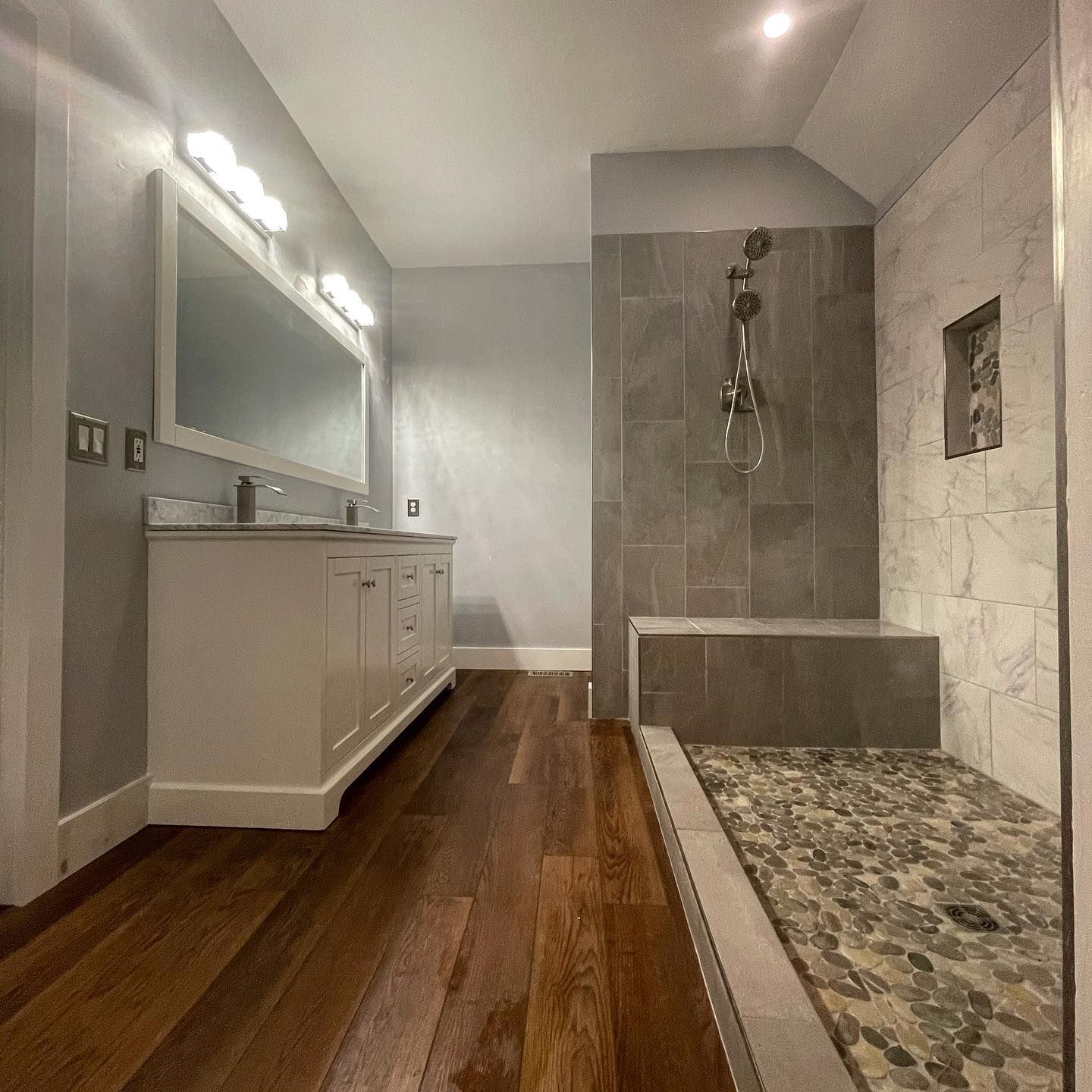 A bathroom with two sinks and a walk in shower
