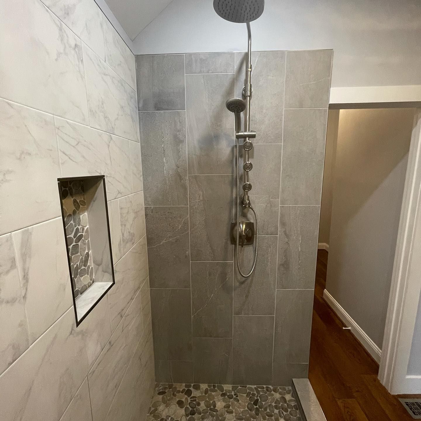 A bathroom with a walk in shower and a shower head.