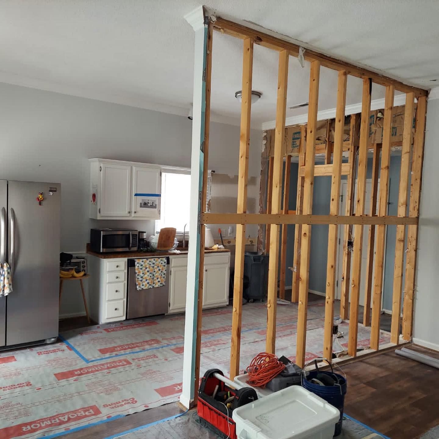 A kitchen is being remodeled with a stainless steel refrigerator.