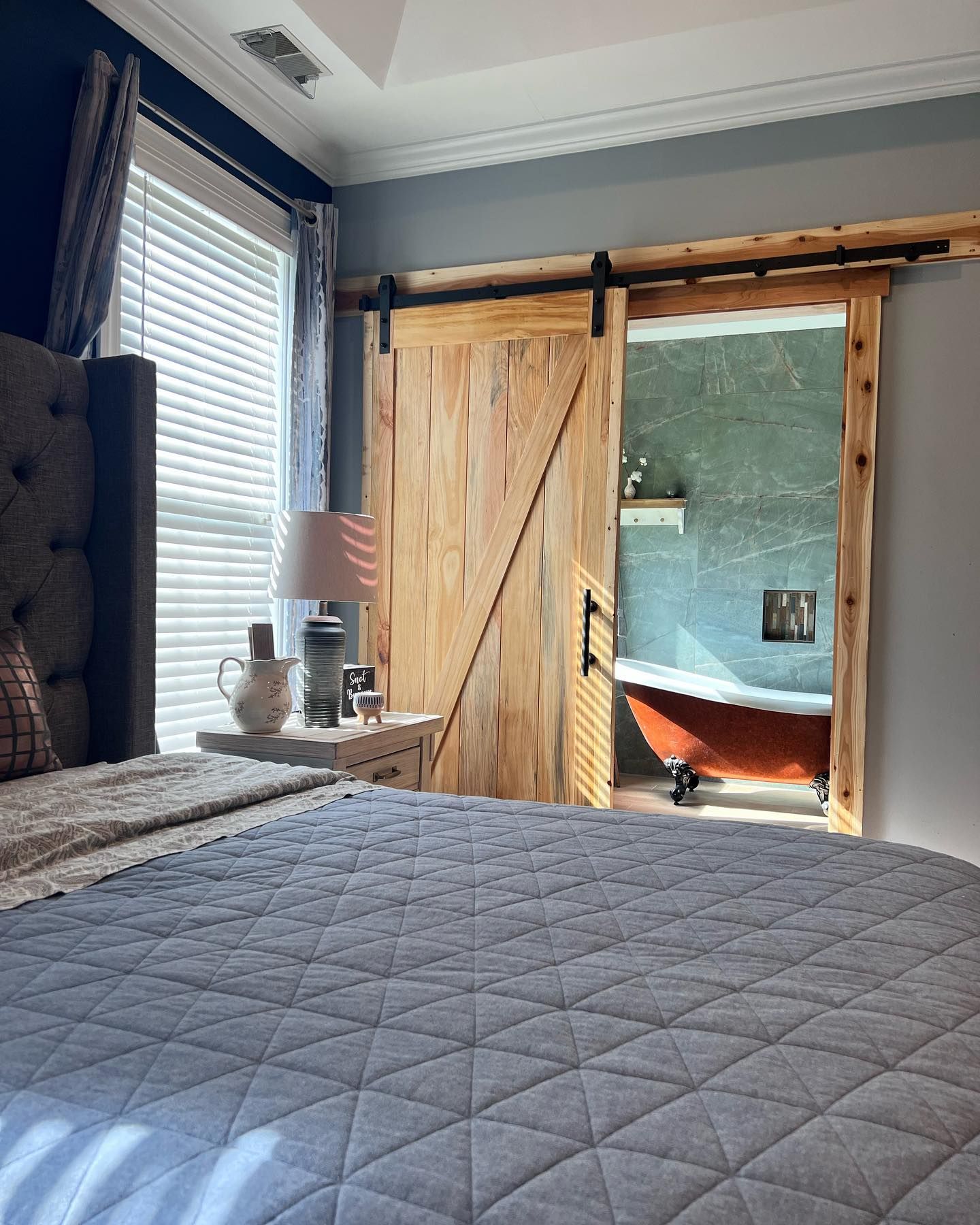 A bedroom with a sliding barn door leading to a bathroom.
