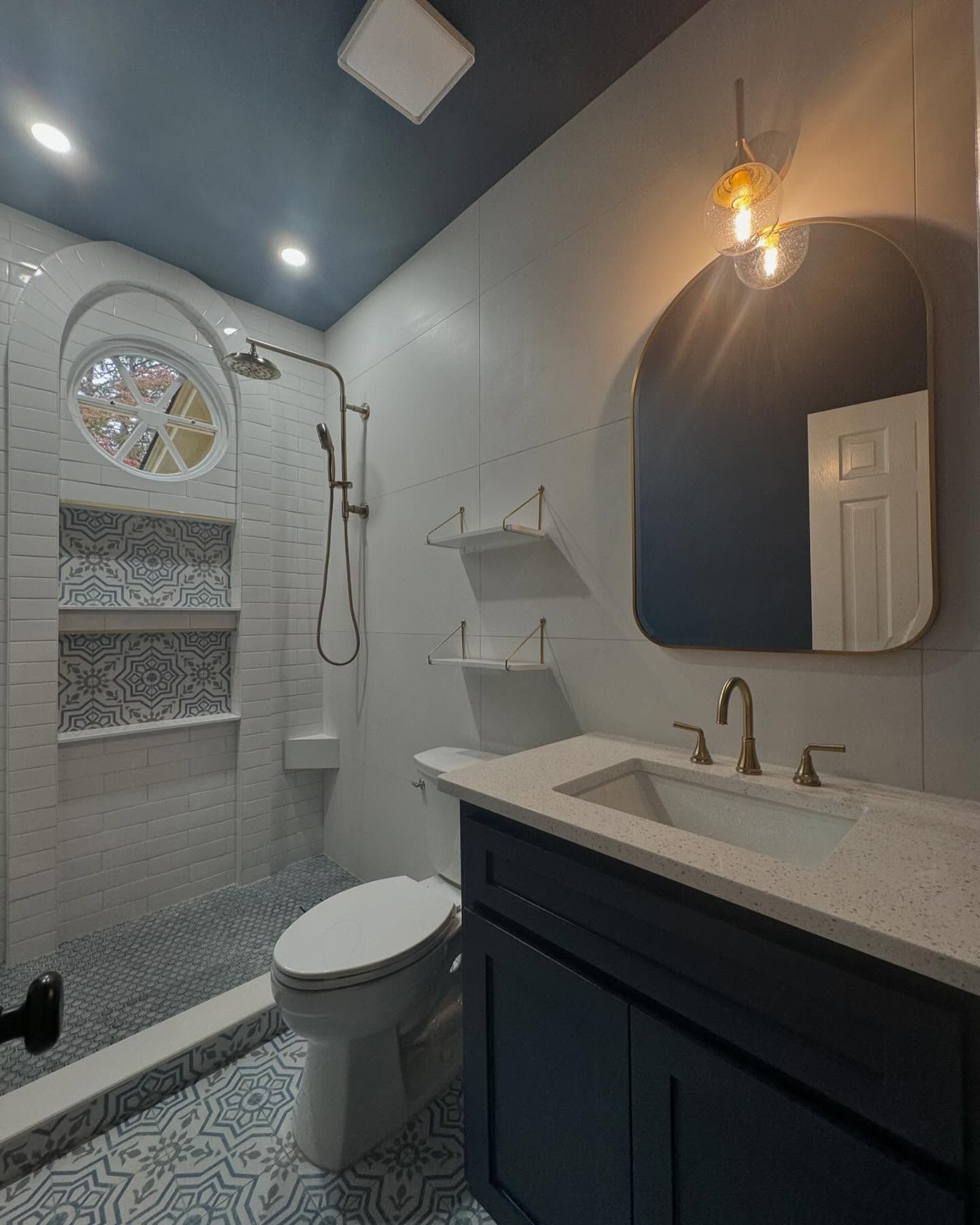 A bathroom with a toilet , sink , mirror and shower.