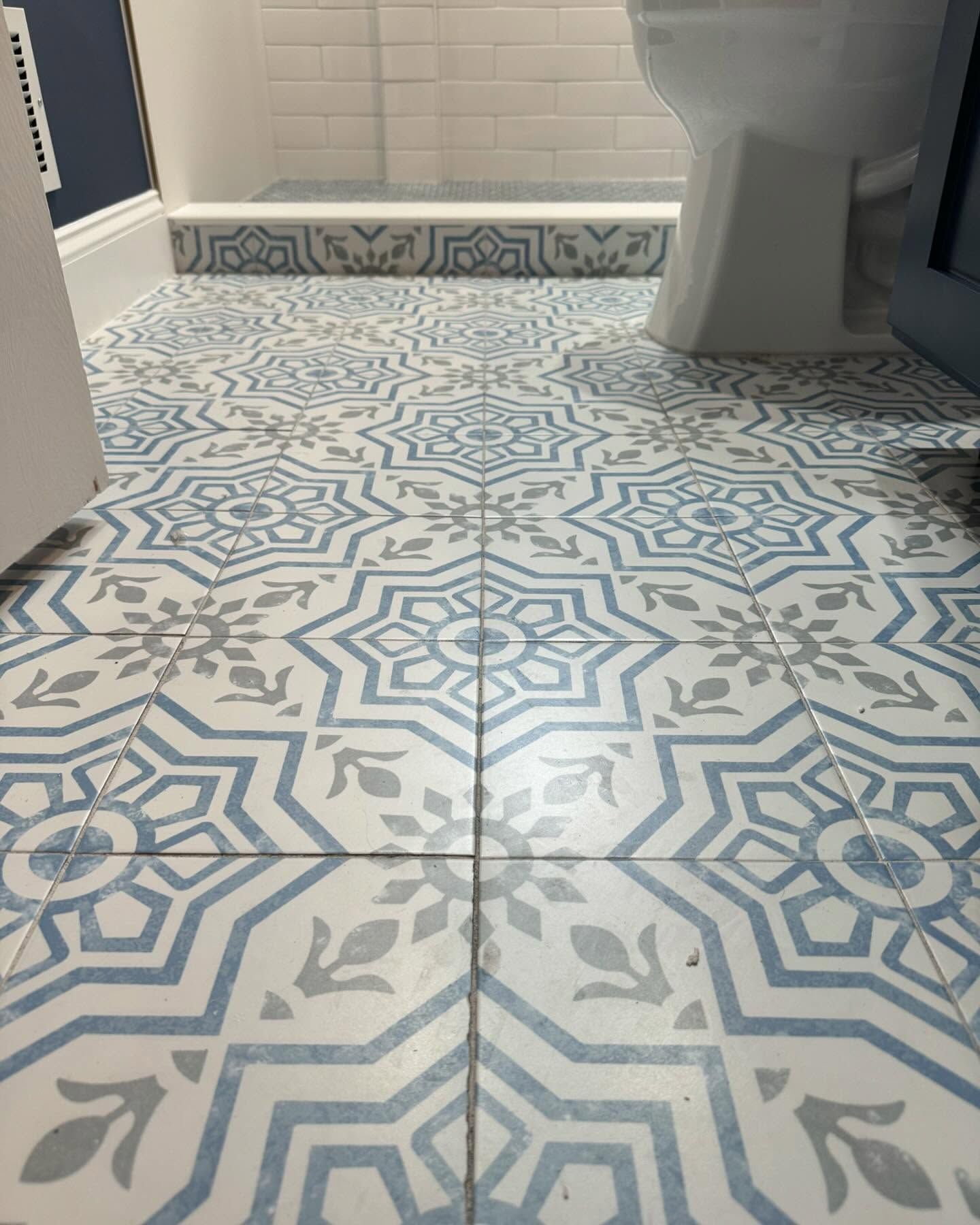 A bathroom floor with blue and white tiles and a toilet