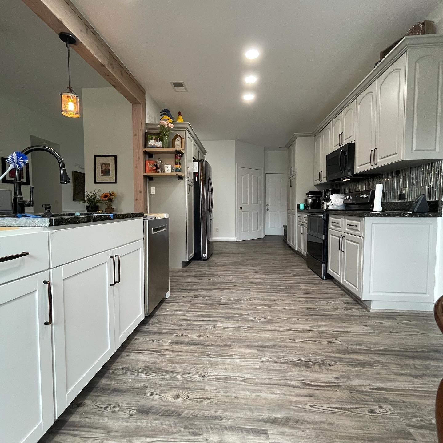 A kitchen with white cabinets , stainless steel appliances , and a wooden floor.
