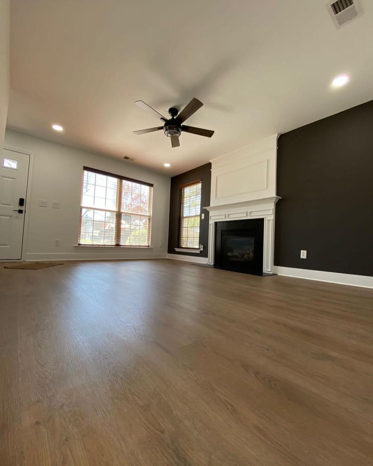 An empty living room with a fireplace and ceiling fan.