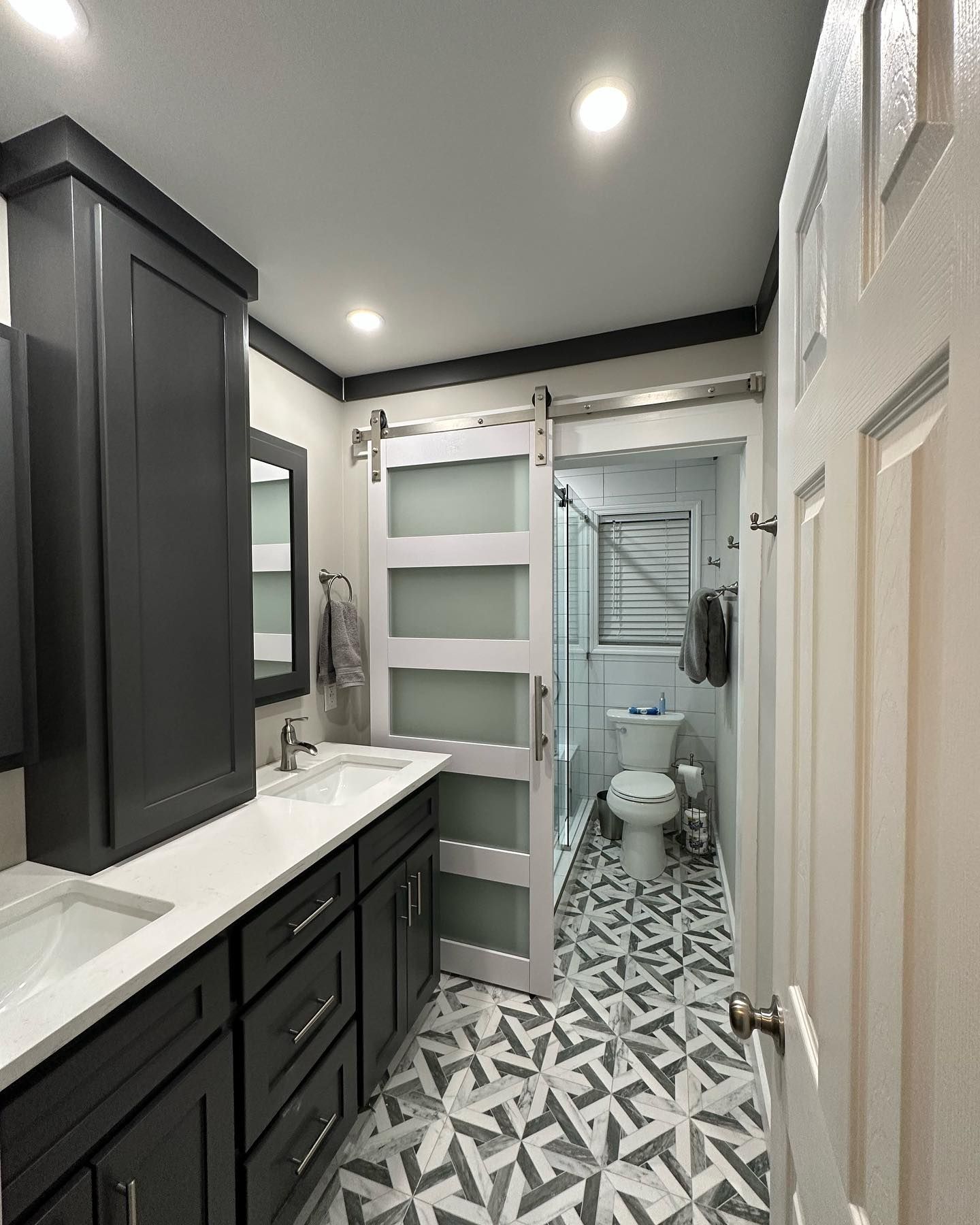A bathroom with a toilet , sink , mirror and sliding barn door.