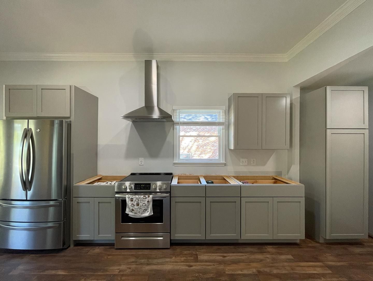 A kitchen with stainless steel appliances and gray cabinets.