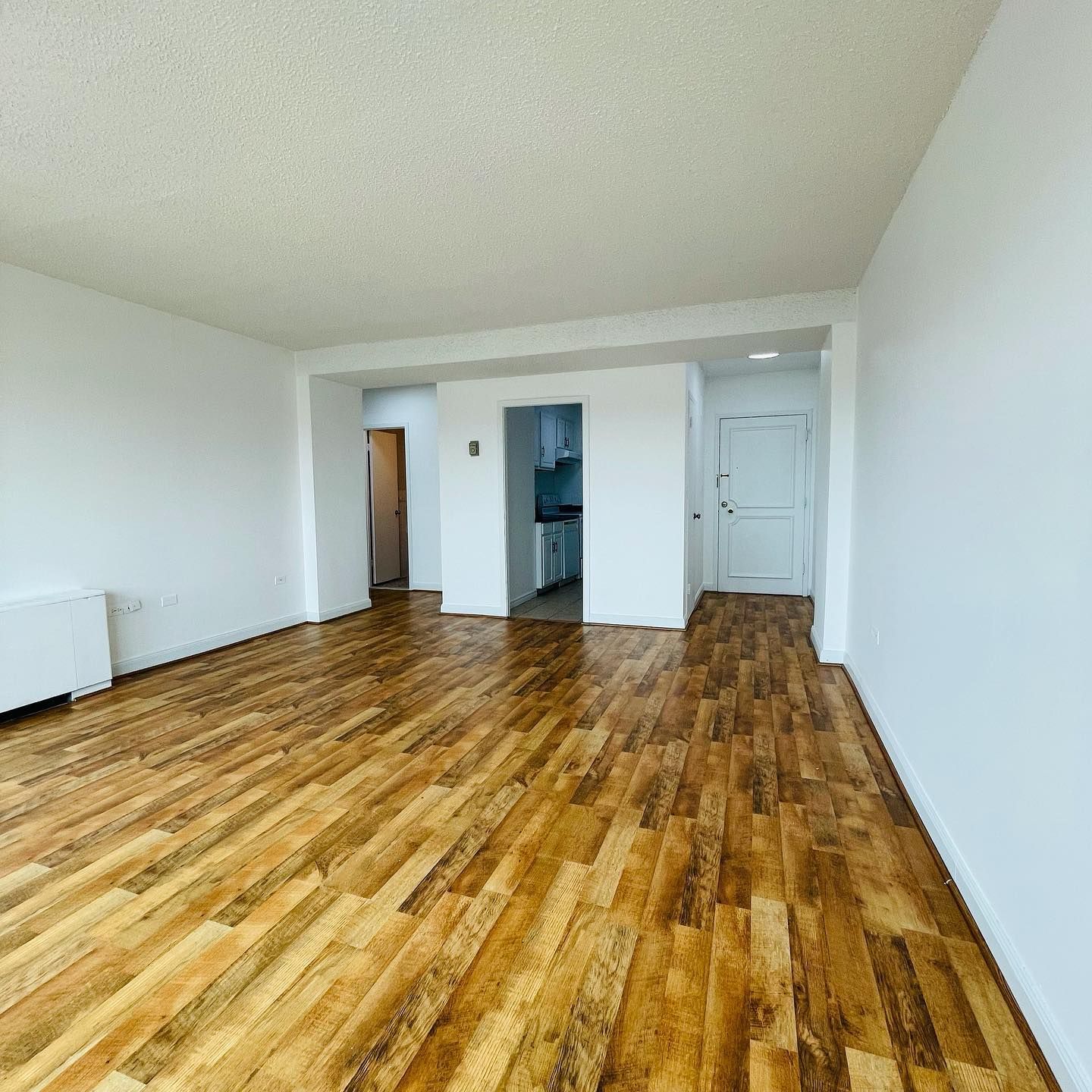 An empty living room with wooden floors and white walls