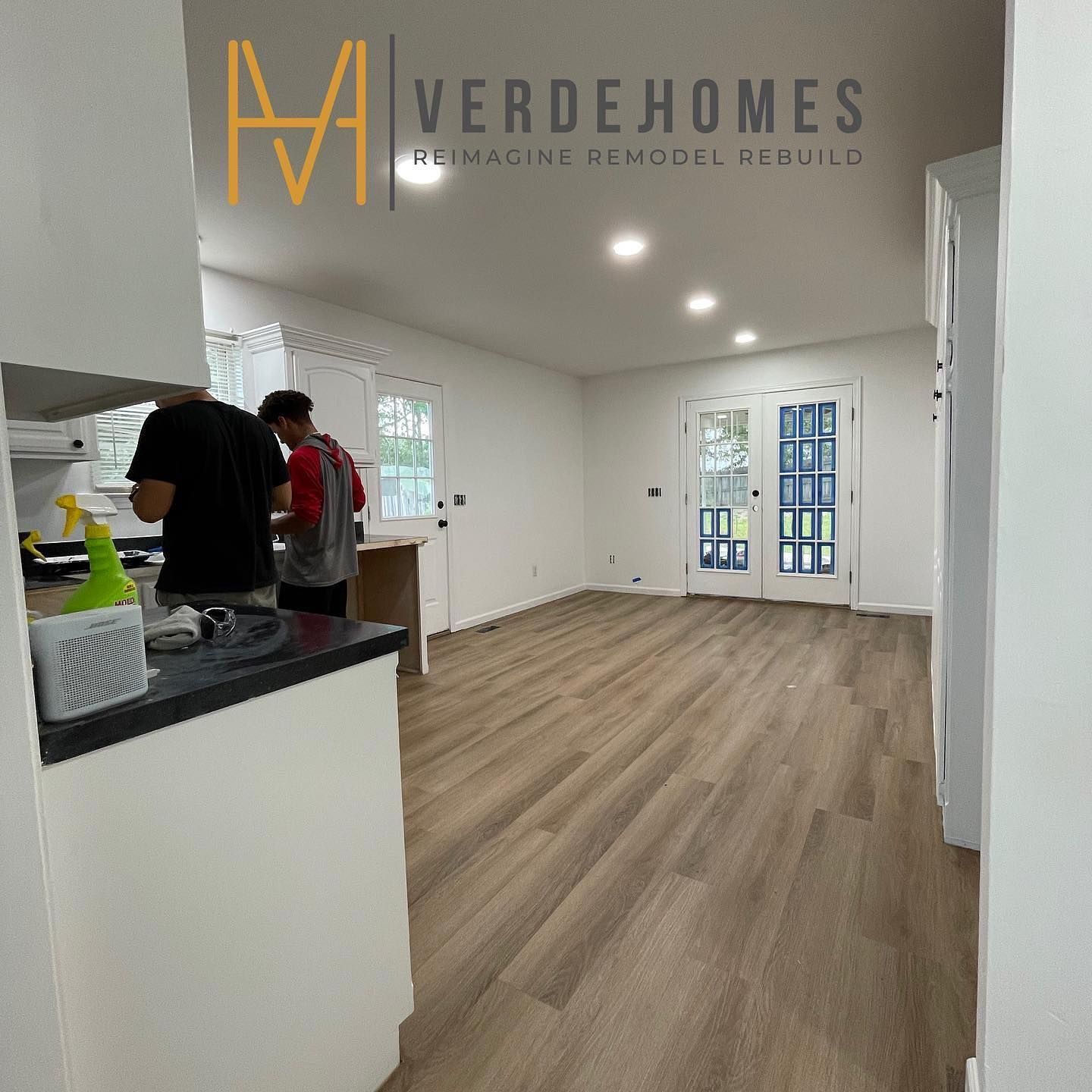Two men are working in a kitchen with the word verdehomes on the wall