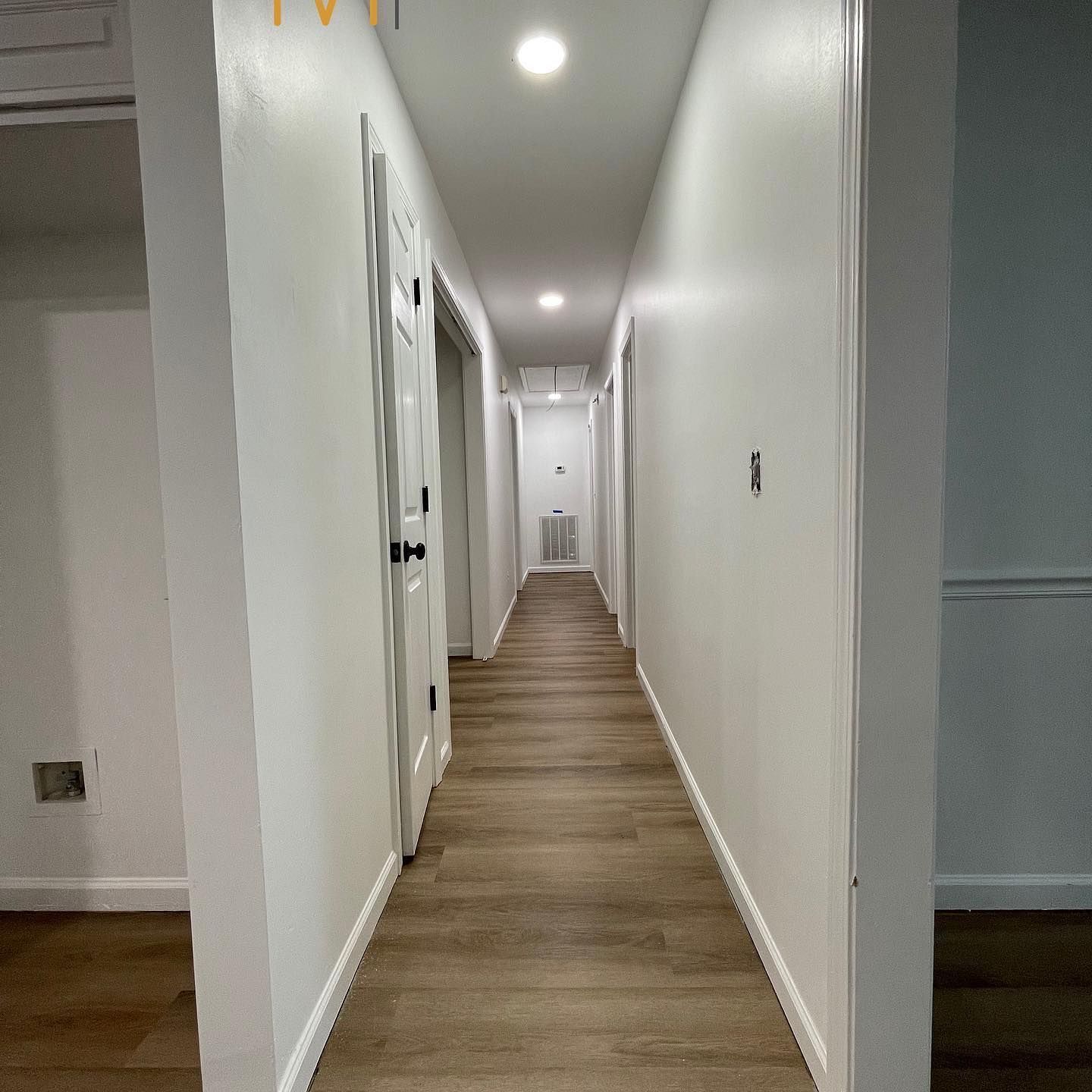 A long hallway with wooden floors and white walls