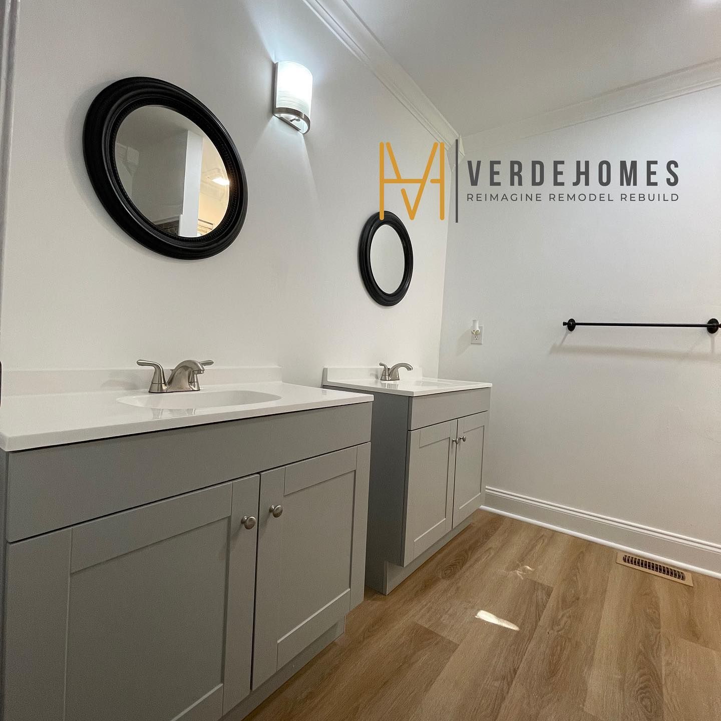 A bathroom with two sinks and a green homes logo on the wall