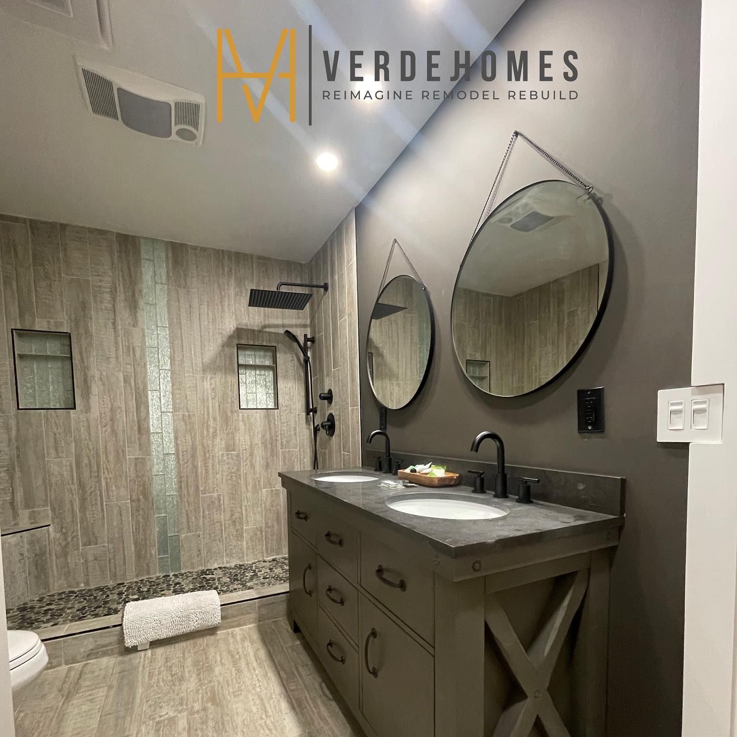 A bathroom with two sinks , two mirrors and a shower.