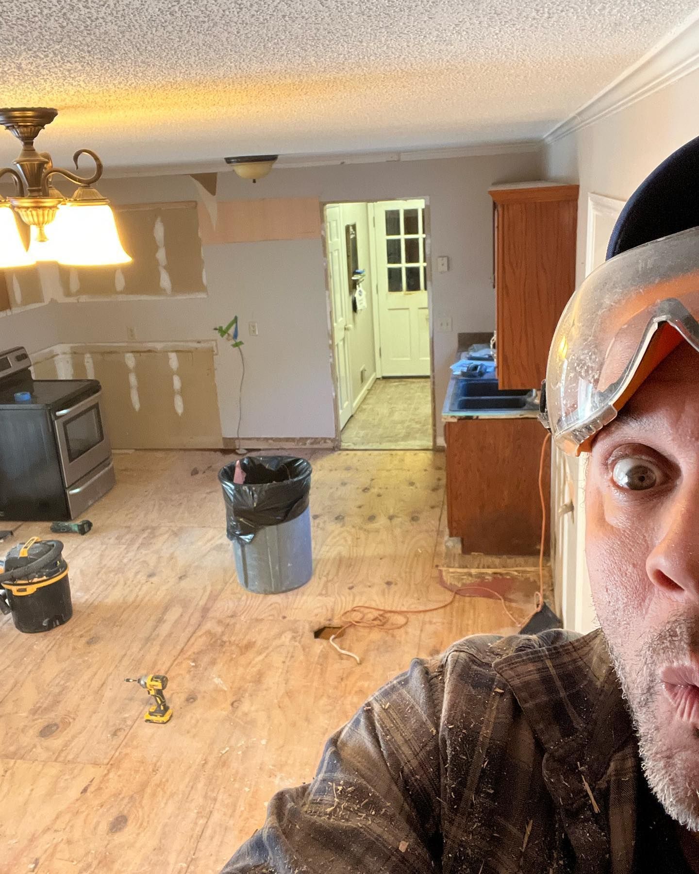 A man wearing goggles is taking a selfie in a kitchen