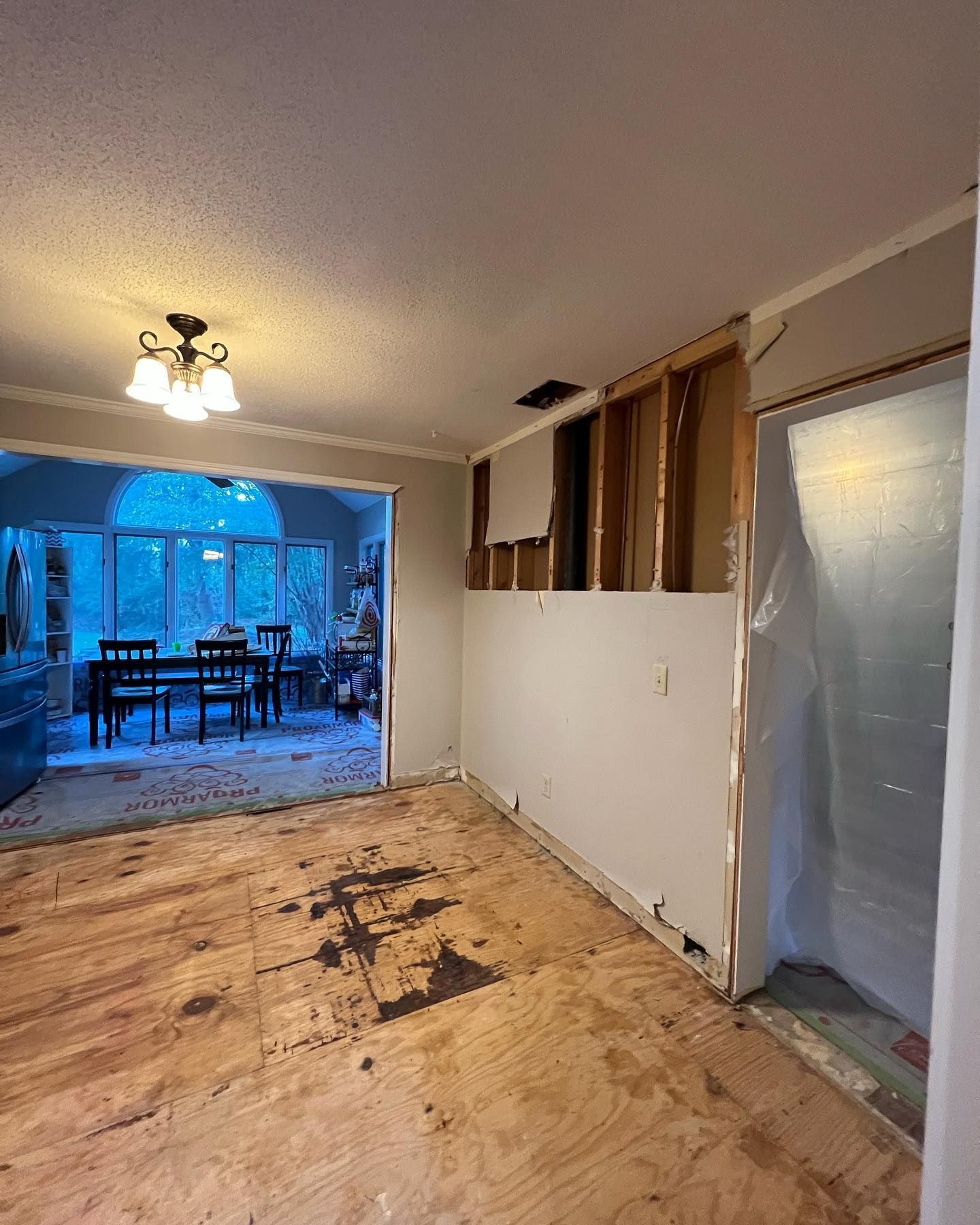 A living room with a wooden floor and a dining room in the background.
