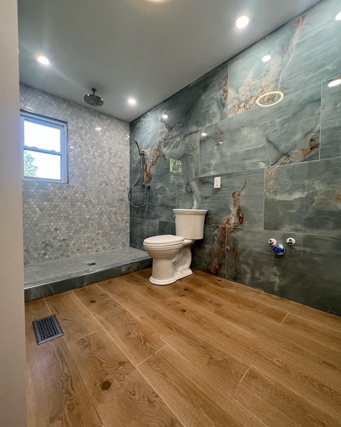 A bathroom with a toilet , shower and wooden floor.
