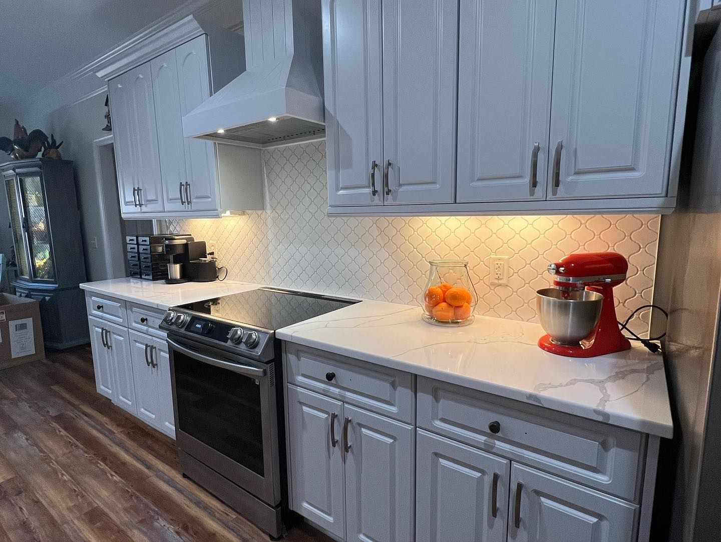 A kitchen with white cabinets , stainless steel appliances , and a red mixer.