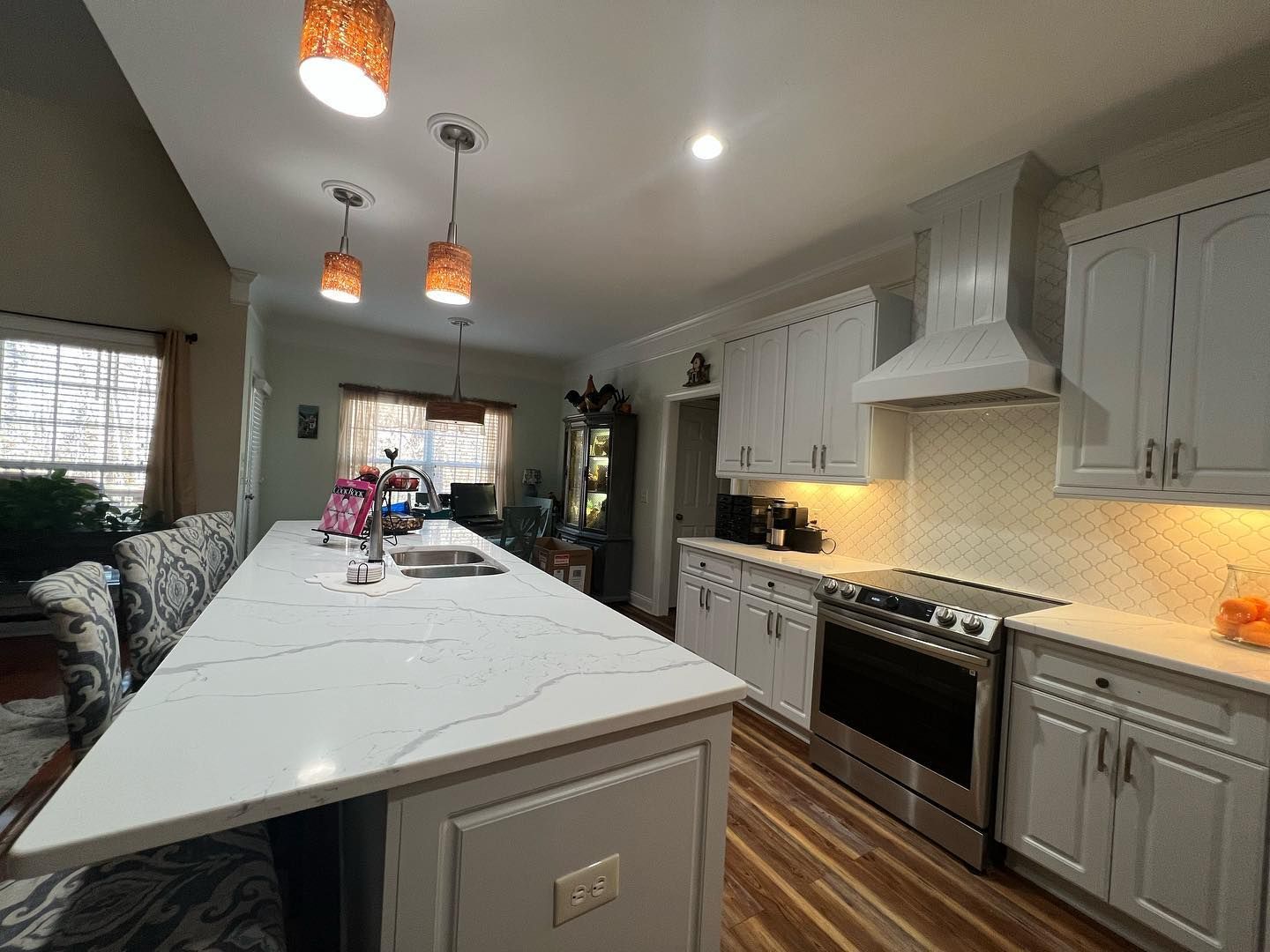 A kitchen with white cabinets , stainless steel appliances , and a large island.