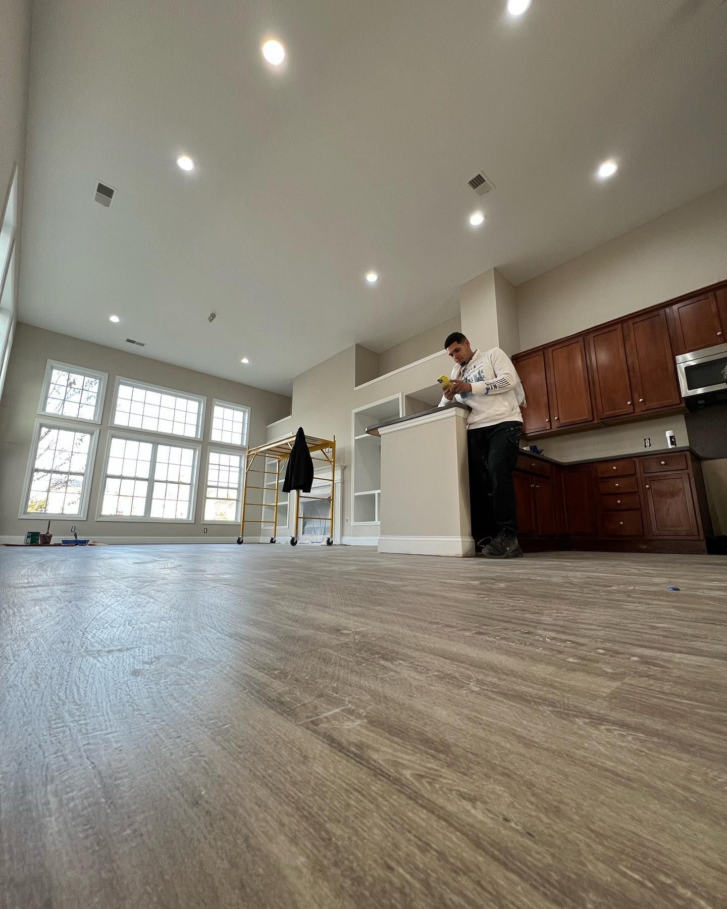 A man is standing in a kitchen looking at a tablet.
