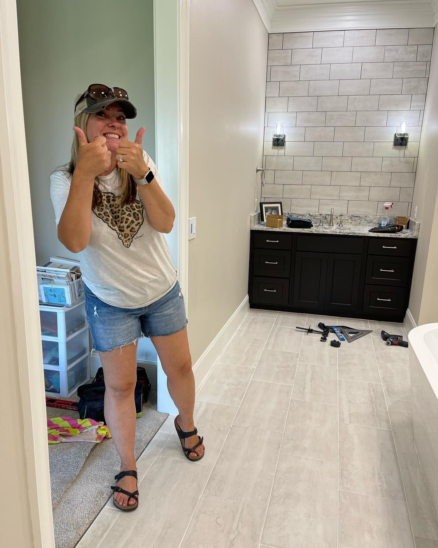 A woman is giving a thumbs up in a bathroom.
