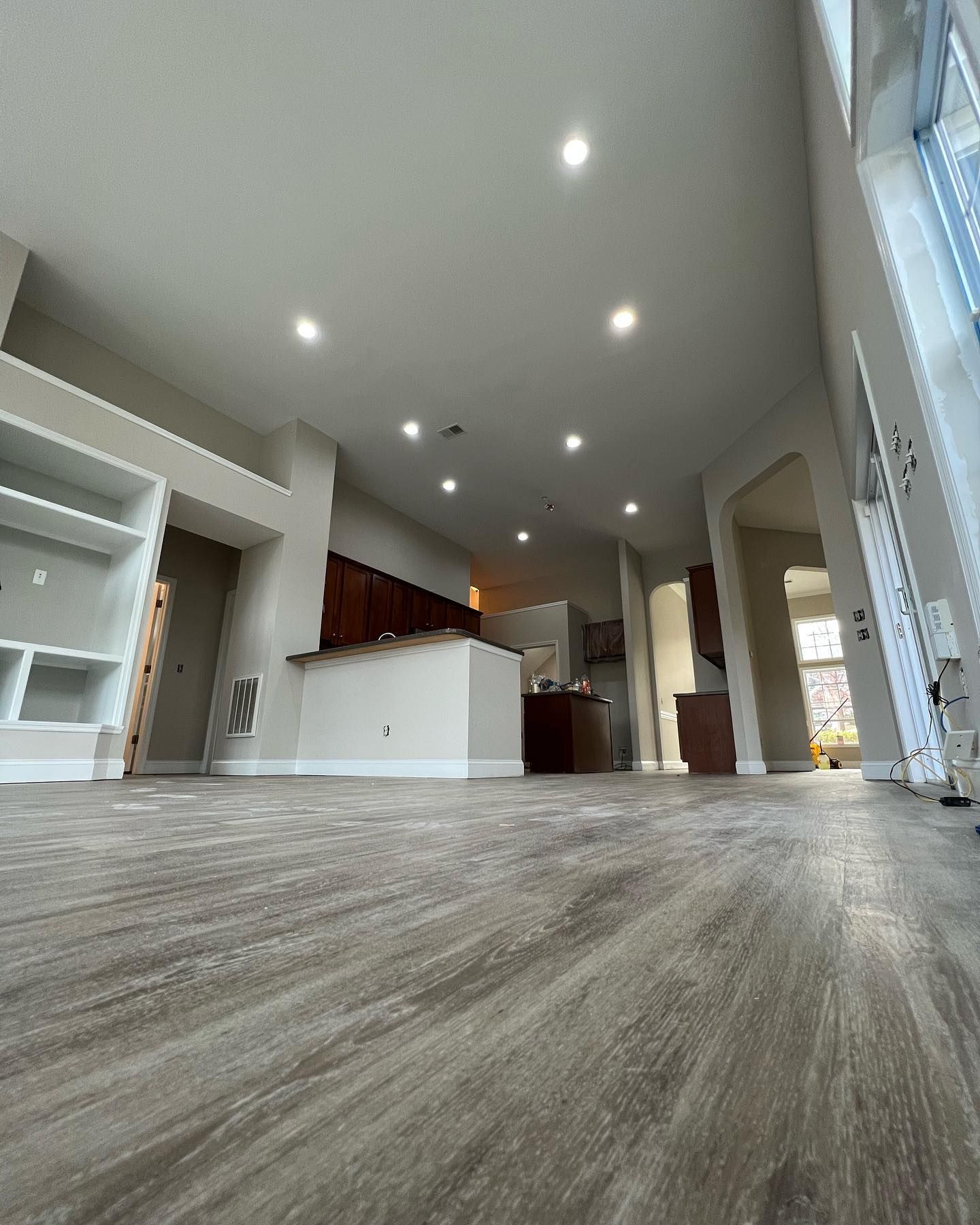 A living room with hardwood floors and a kitchen in the background.