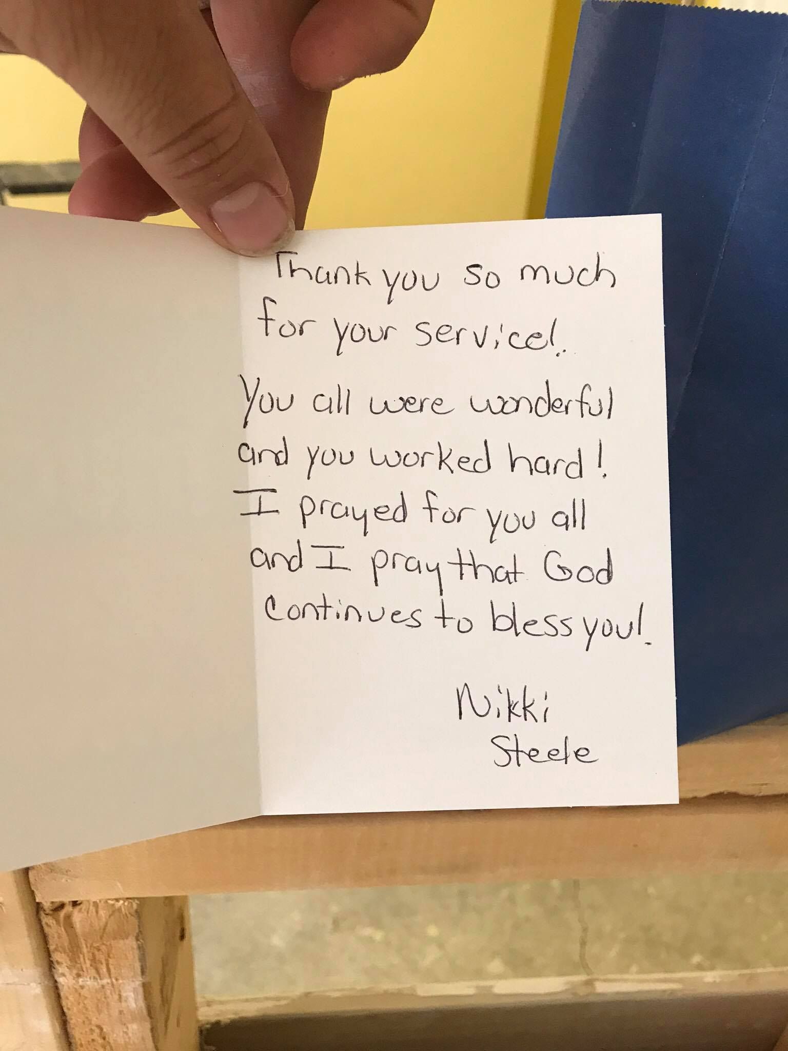 A person is holding a piece of paper with a handwritten message on it
