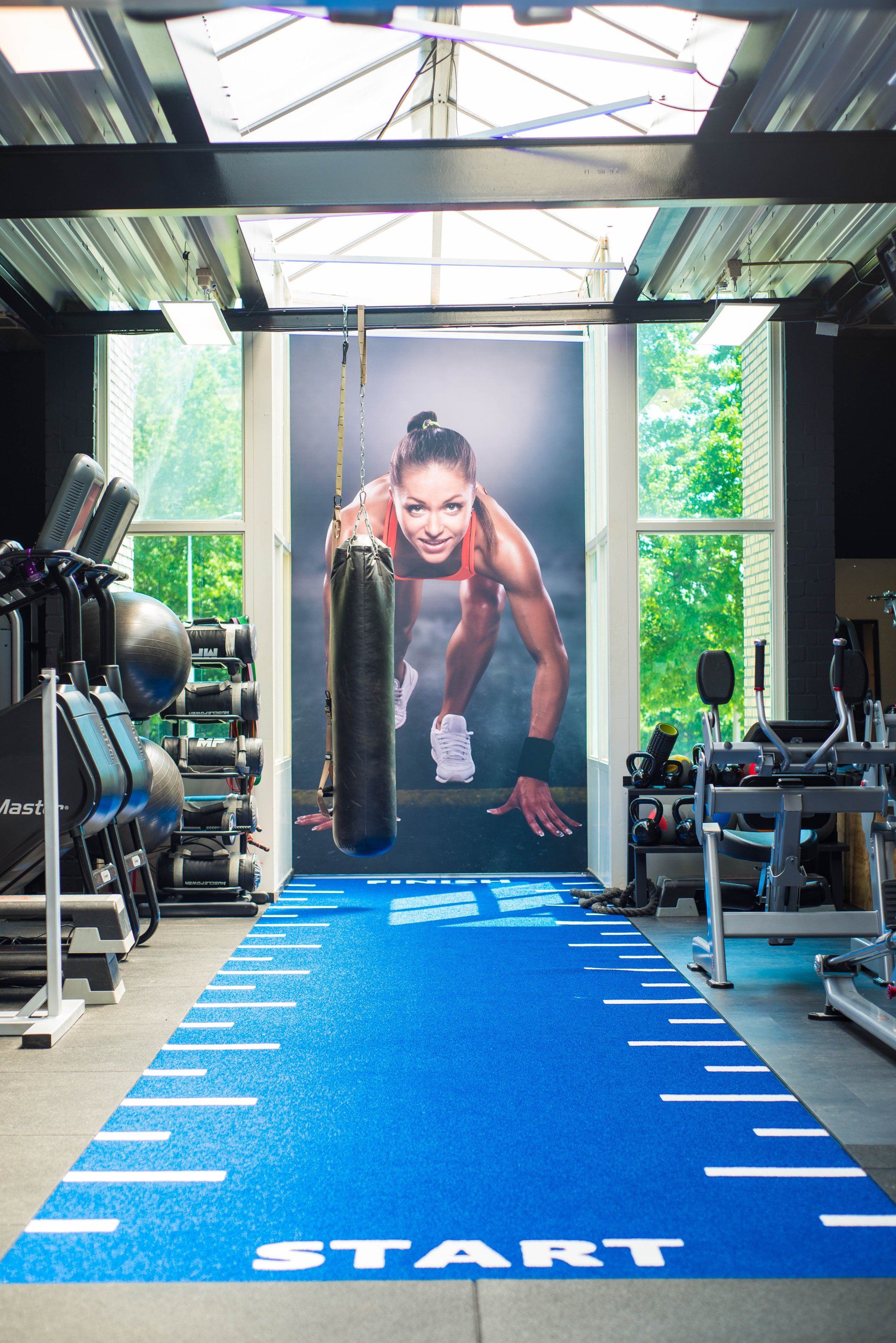 een gymzaal met een blauwe mat en een foto van een vrouw aan de muur.