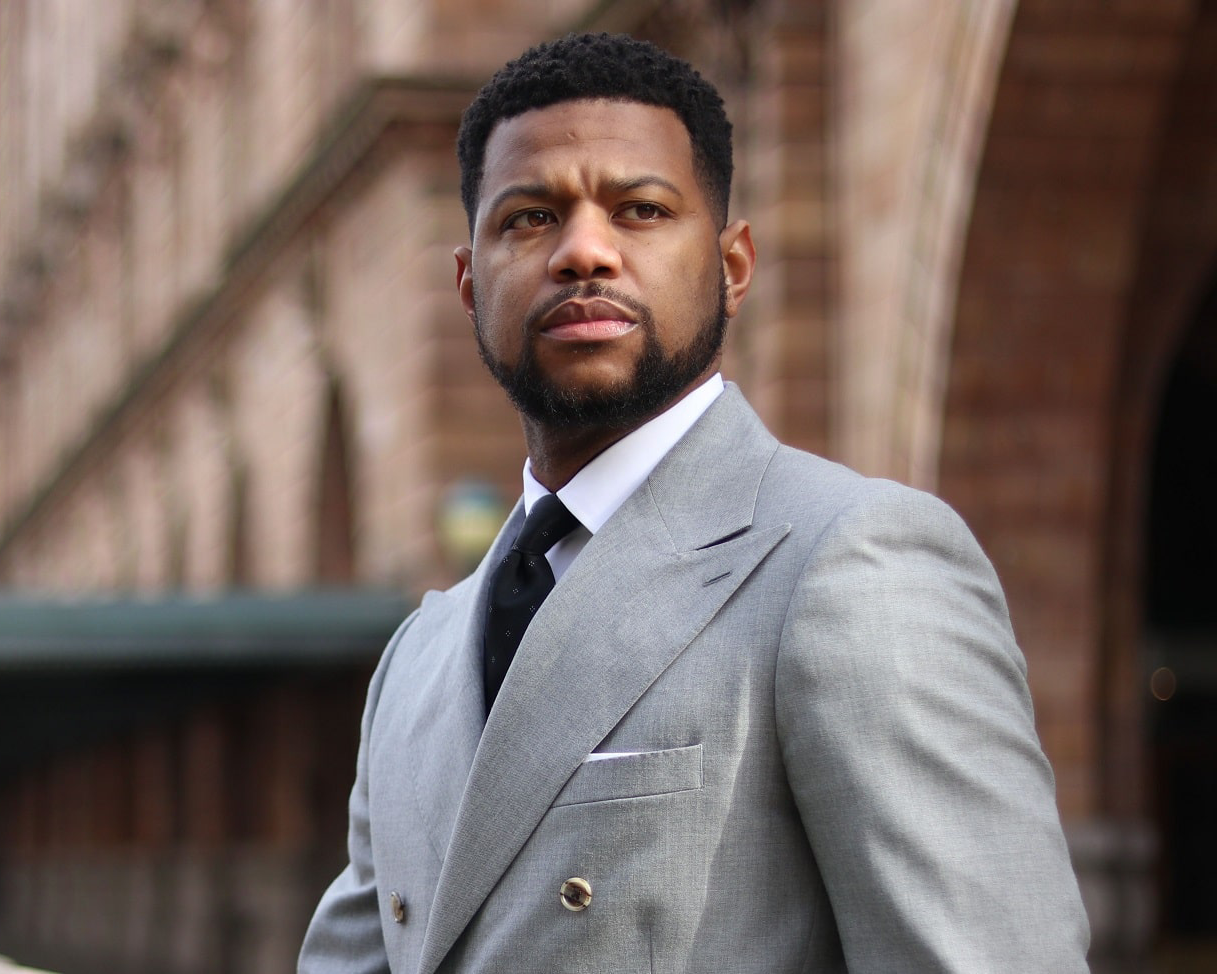 A man in a suit and tie is standing in front of a building.