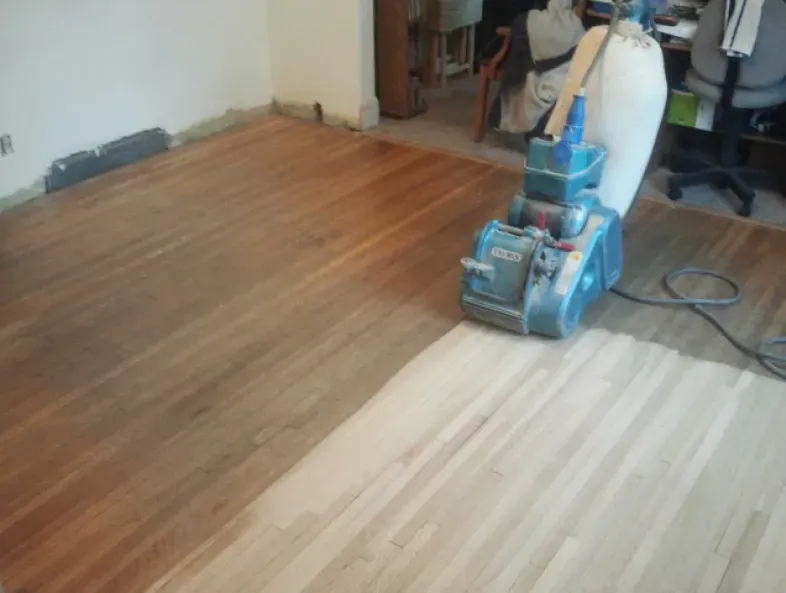 A machine is sanding a wooden floor in a room