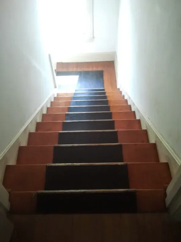 A set of wooden stairs with a black carpet