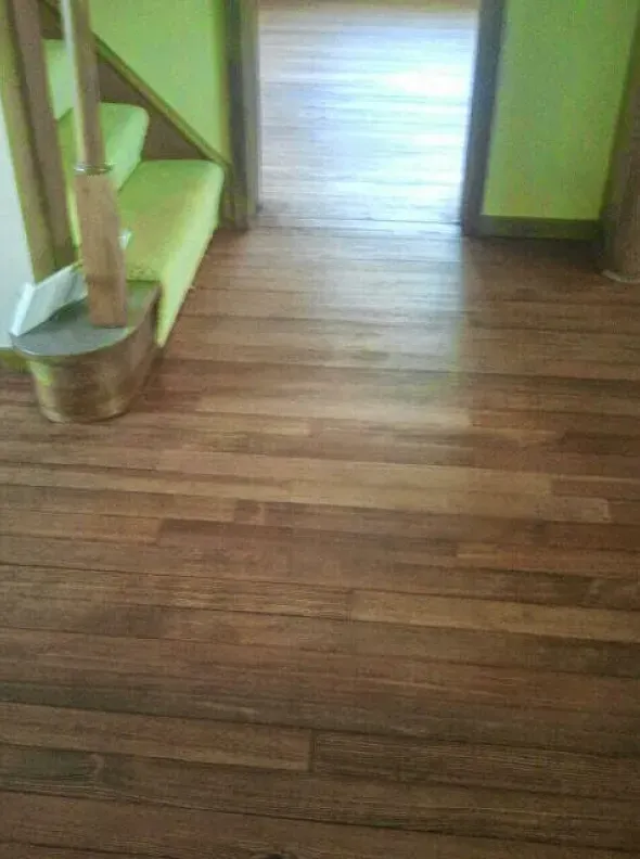 A wooden floor with a green staircase in the background.
