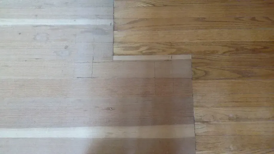 A close up of a wooden floor with two different shades of wood.