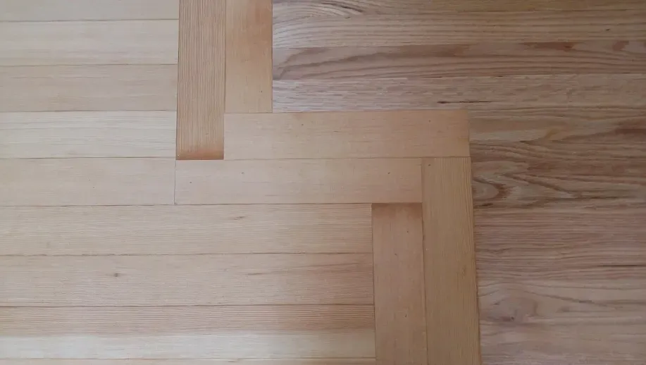A close up of a wooden floor with a herringbone pattern.