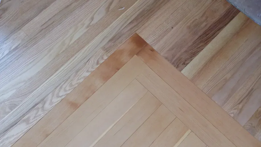 A close up of a wooden floor with a herringbone pattern.