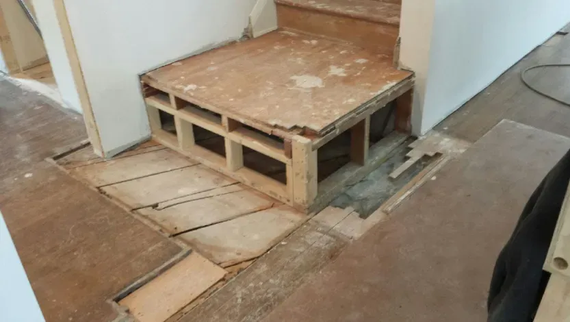 A wooden staircase is being built in a room.